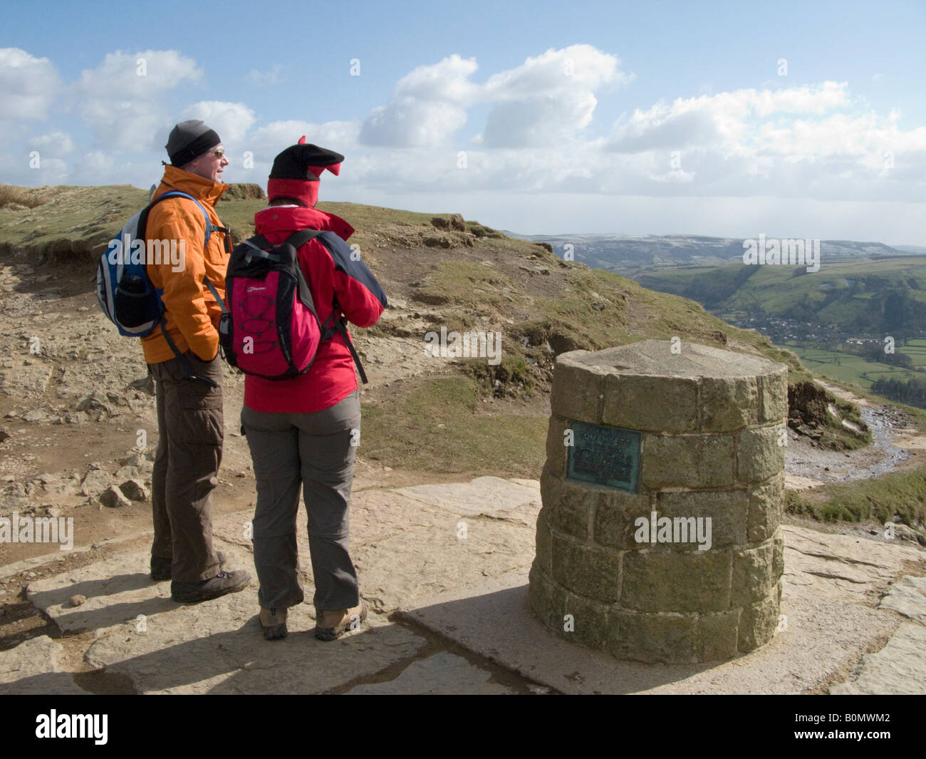 Couple look southwards from a memorial to Tom Hyett at Hollins Cross on Mam Tor path. Peak District National Park. Derbyshire UK Stock Photo