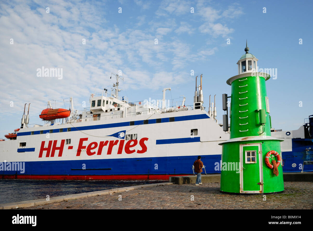 A man from behind near the green lighthouse and a ferry at the harbour of Helsingor Denmark May 2007 Stock Photo