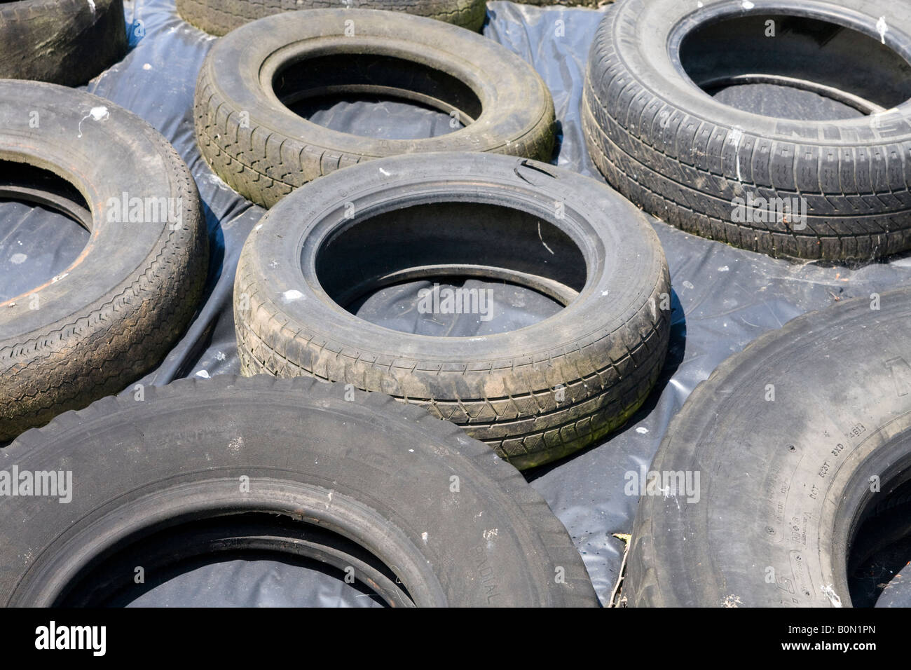 Used tyres holding down a polythene sheet on a silage pit Stock Photo