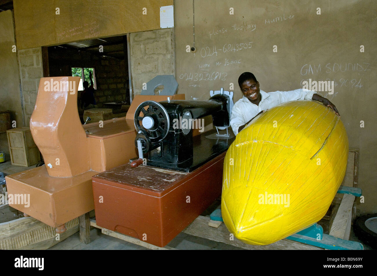Coffin carpenter with coffins shaped like a  carpenter's plane, a sewing machine  and a cacao fruit, Kuluedor, Ghana Stock Photo