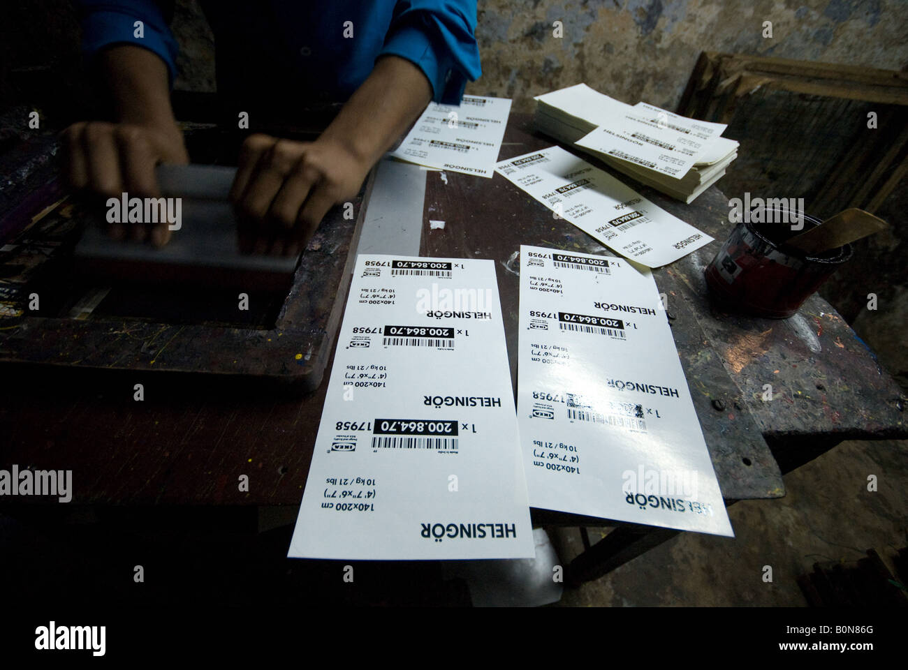Worker screen printing labels for Ikea in back streets of Godualia the old city Varanasi India Stock Photo