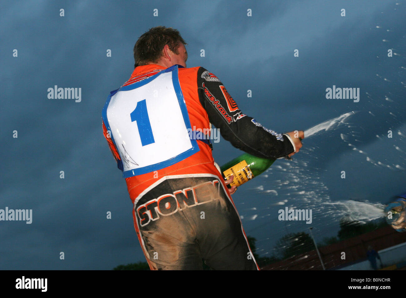 a speedway rider celebrates a victory by spraying champagne Stock Photo