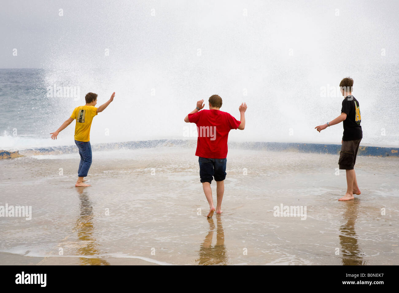 Breaking waves Three Teenagers Dodging Breaking Waves and sea spray on ...
