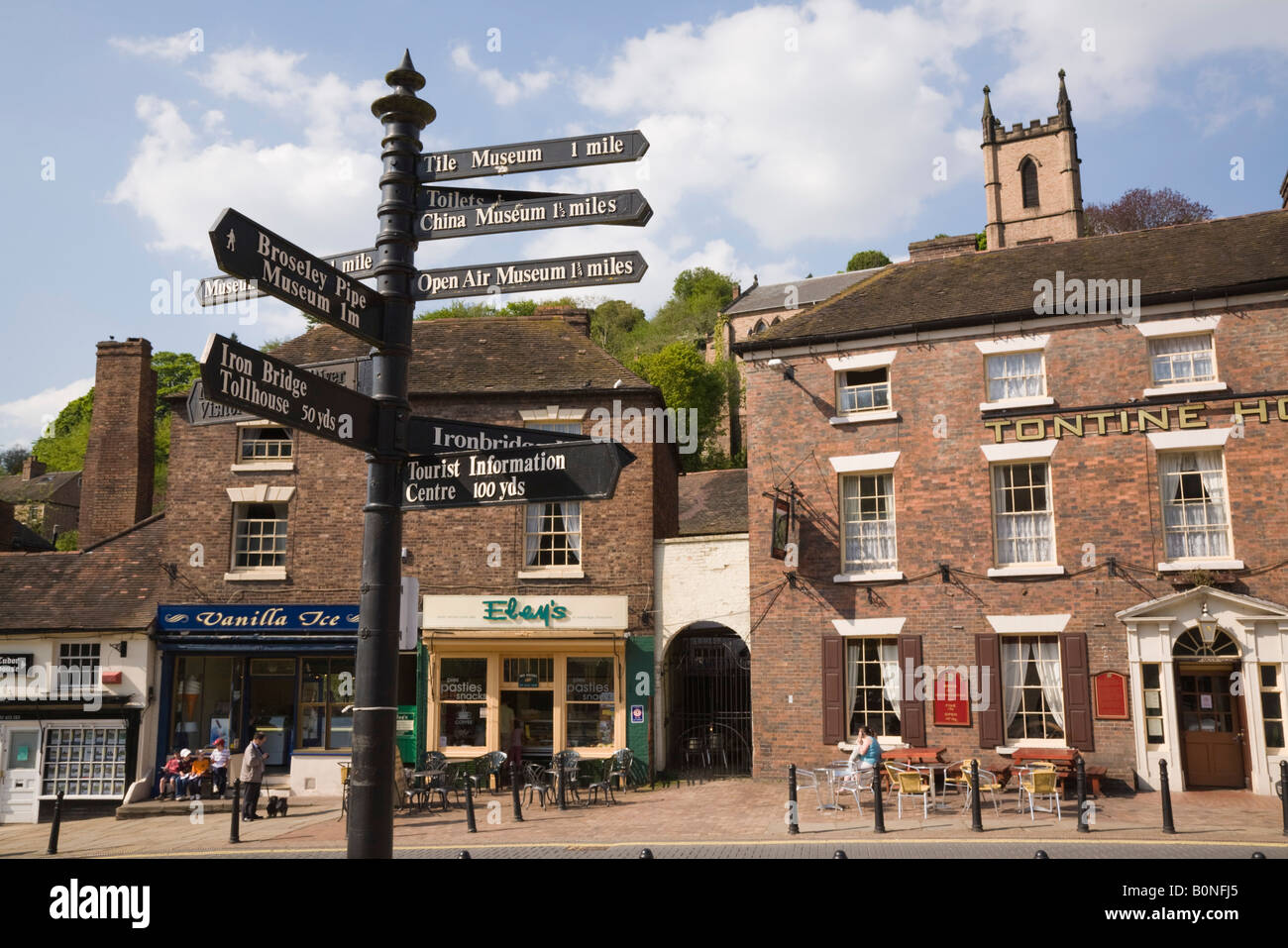 Tourist direction signpost by hotel and shops on Tontine Hill in town centre. Ironbridge Shropshire West Midlands England UK Britain Stock Photo