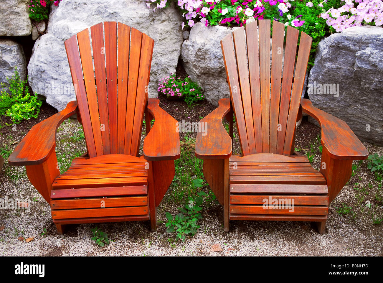 Two solid wood patio chairs and natural stone landscaping Stock Photo