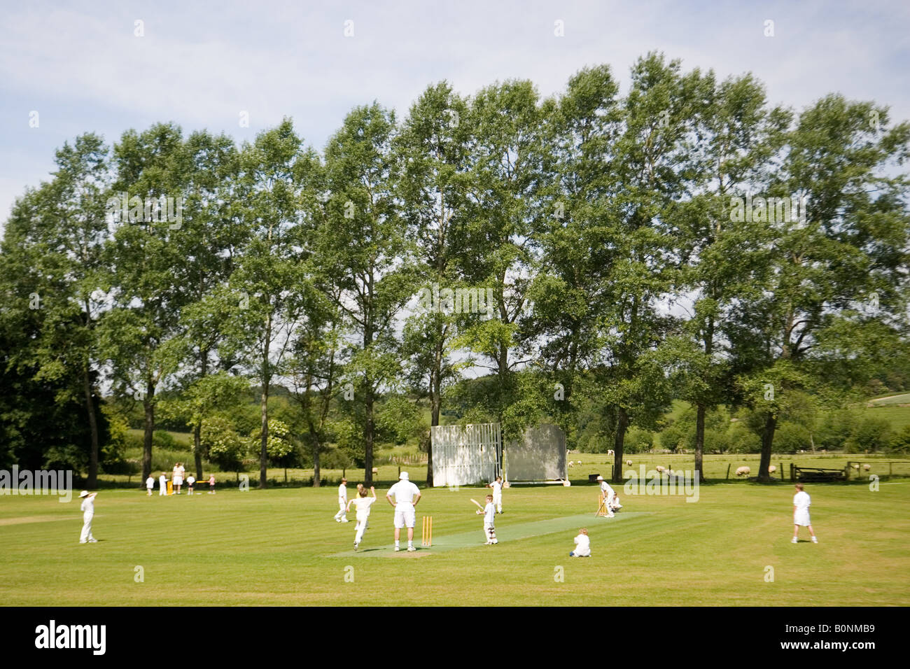 Children play cricket on village pitch Swinbrook The Cotswolds England United Kingdom Stock Photo