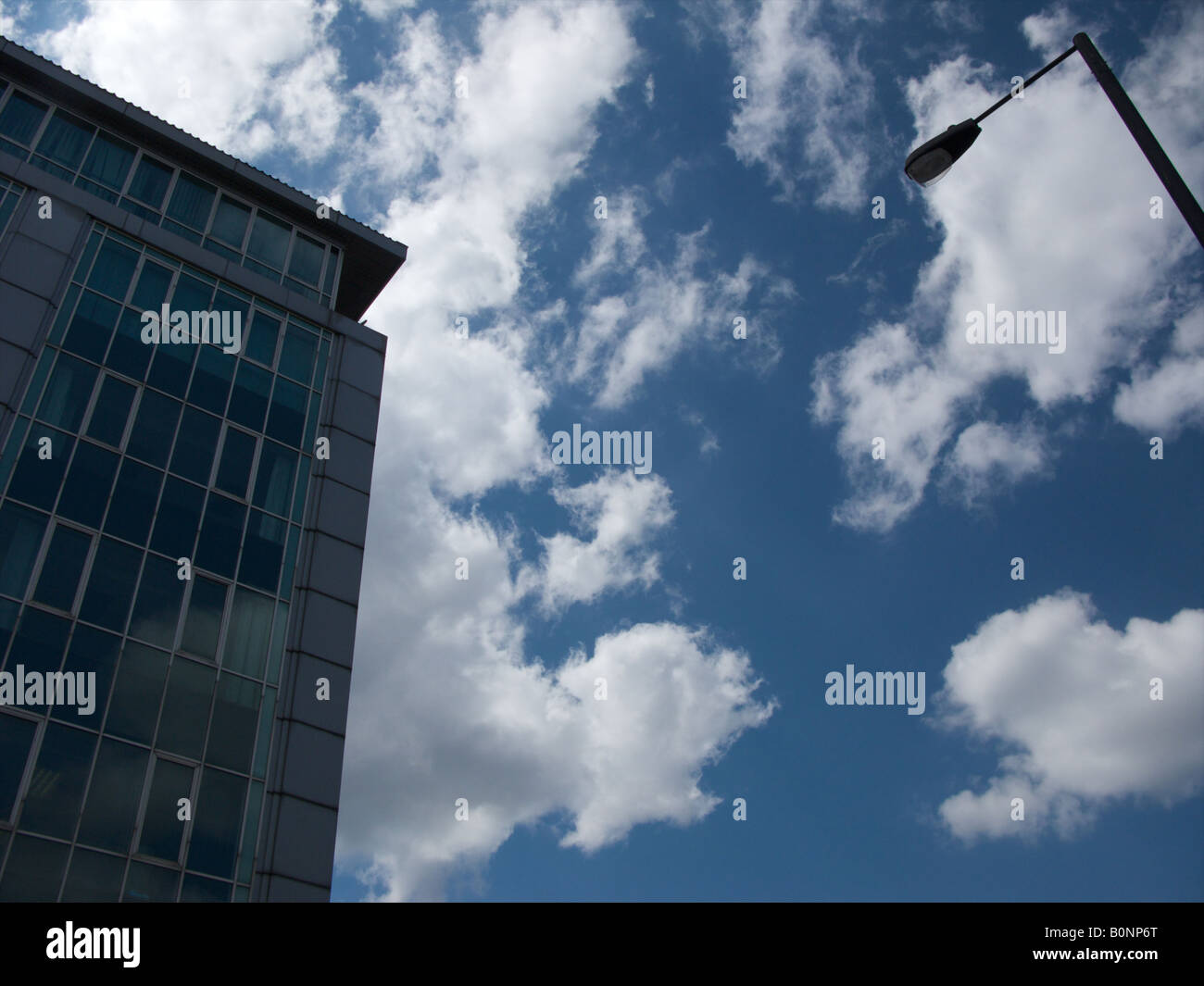 Upward view of street lamp and modern building with stunning cloudy blue sky in background Stock Photo