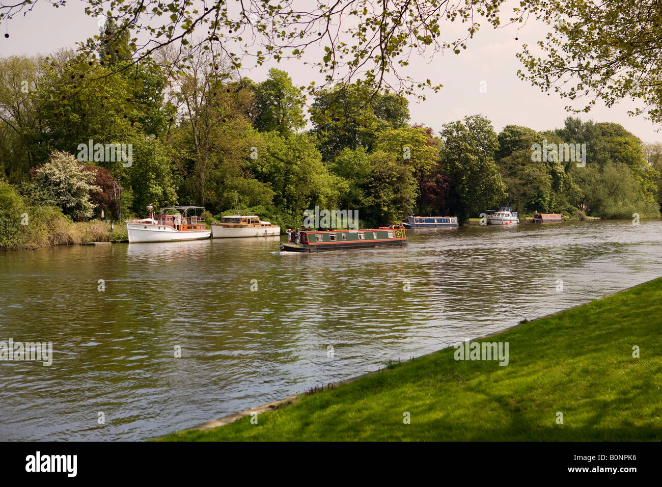 A canal barge sailing past pleasure boats on the River Thames in Berkshire viewed from Windsor Home Park Windsor Castle Stock Photo