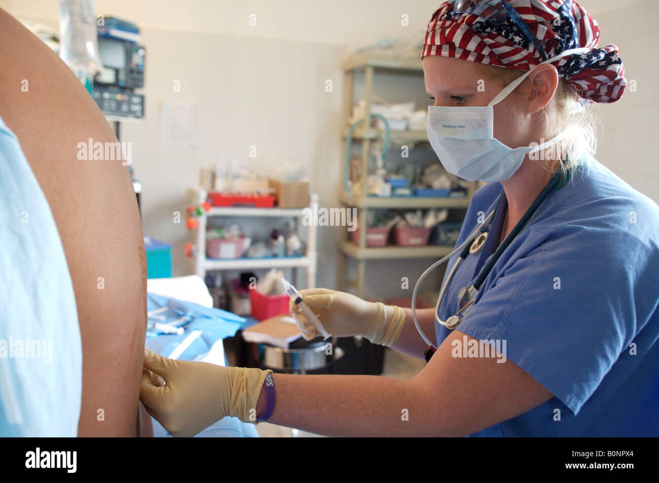 A nurse anesthetist administers a spinal injection while preparing a patient for surgery during a 2006 surgical mission to Sula Stock Photo