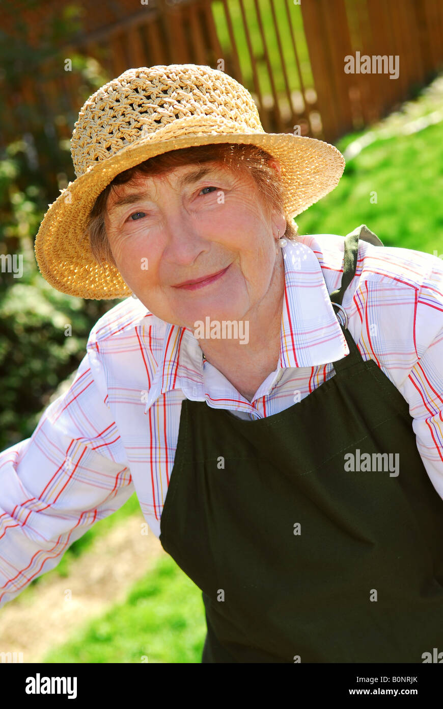 Portrait of a senior woman in gardening apron and hat Stock Photo - Alamy
