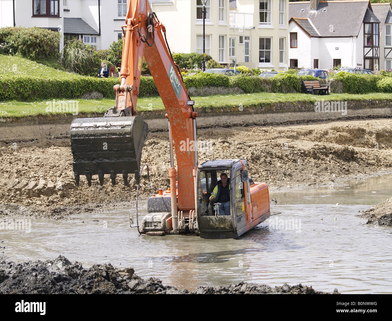 Digger working deep in the mud and water clearing out the bottom of Bude canal, Cornwall, UK Stock Photo
