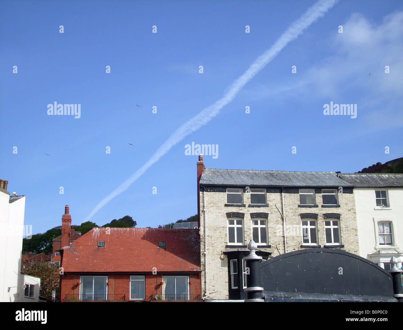 Vapour trail over old town houses in Scarborough, North Yorkshire, England. Stock Photo