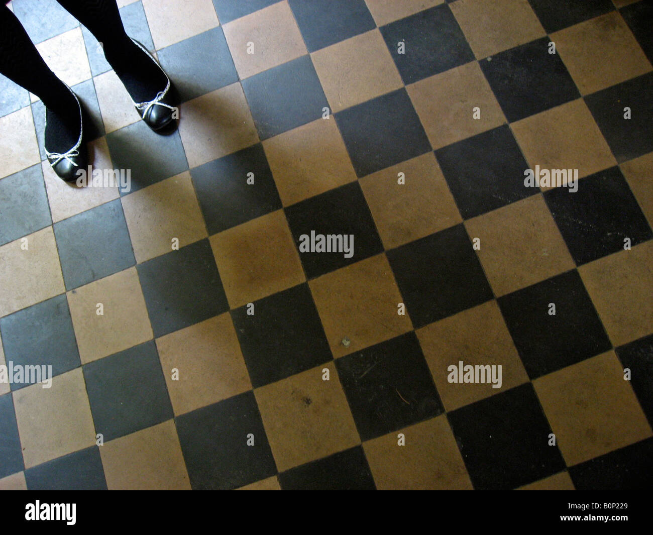 a girls feet stand on check tiled floor Stock Photo
