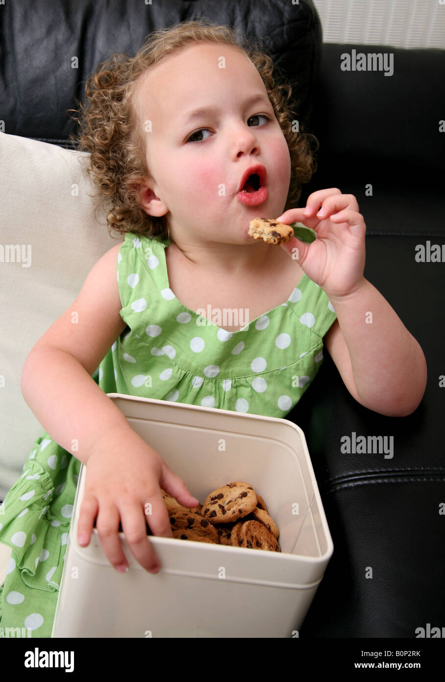 A 3 year old girl sitting on the sofa at home being greeding and