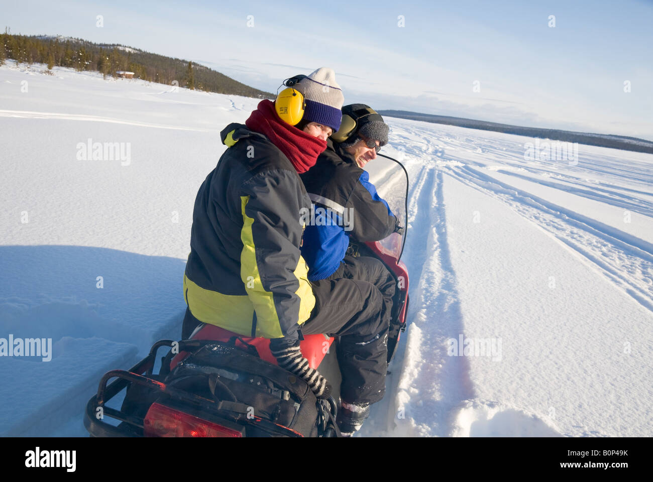 Two women in their fourties ride a Lynx snowmobile in snowy Lapland / northern Sweden Stock Photo