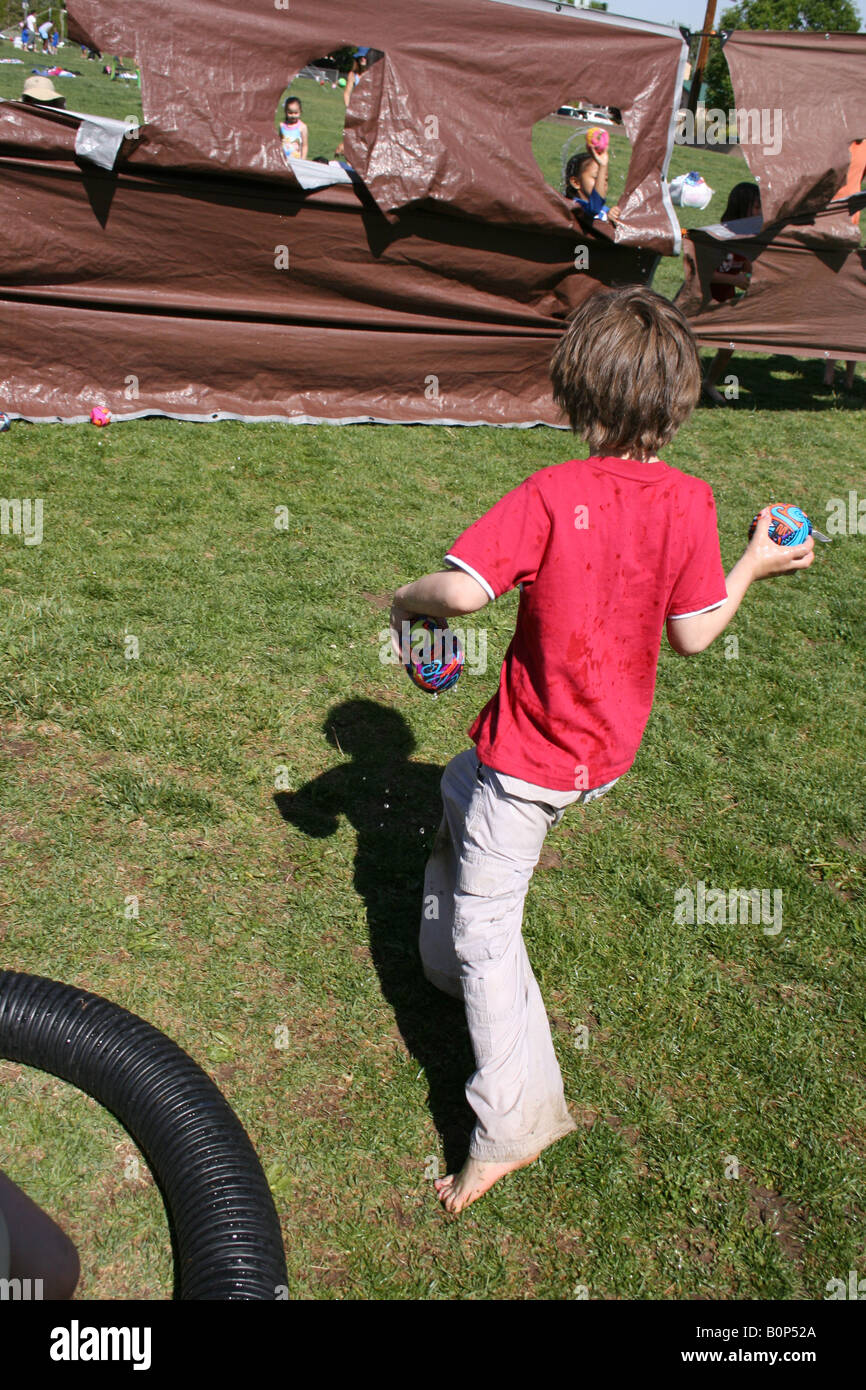 six year old child throwing balls into holes in canvas, outdoor game, field day, school activity, United States Stock Photo