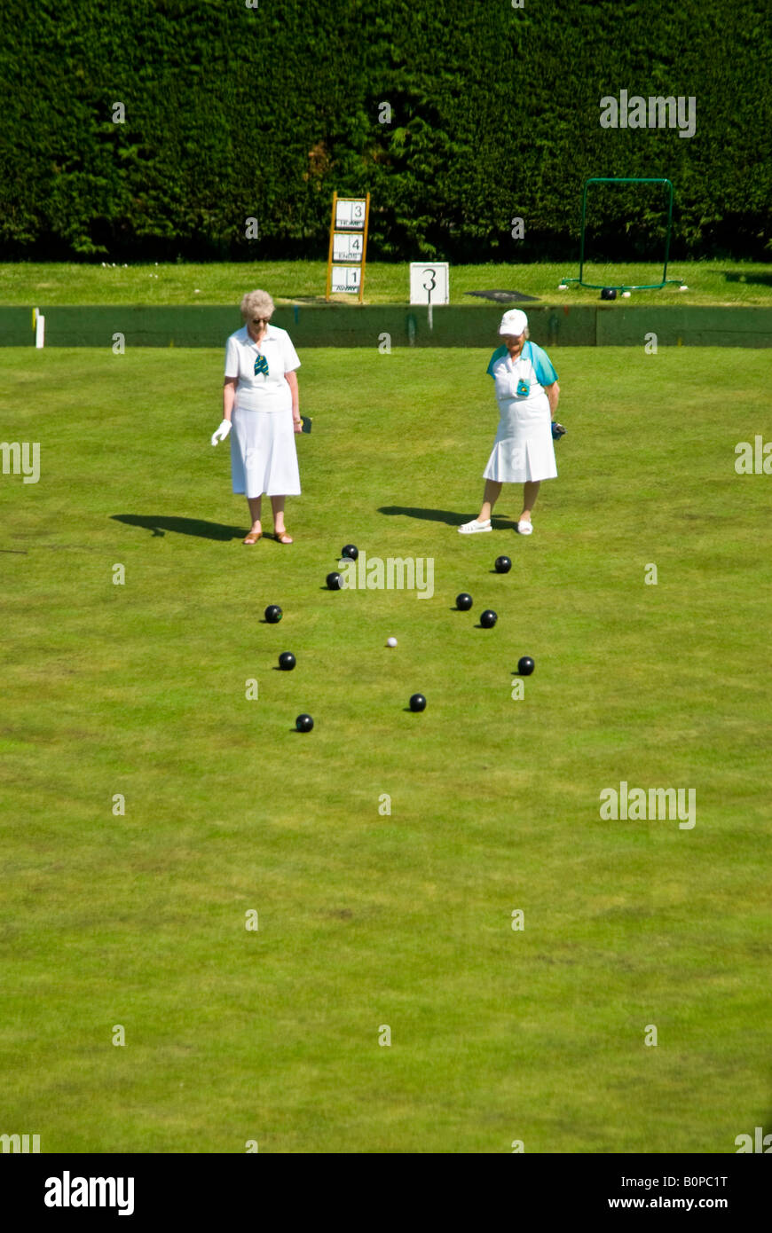 Vertical elevated view of two ladies, the skipper and number 3, at the 'Head' during a game of bowls in the sunshine. Stock Photo