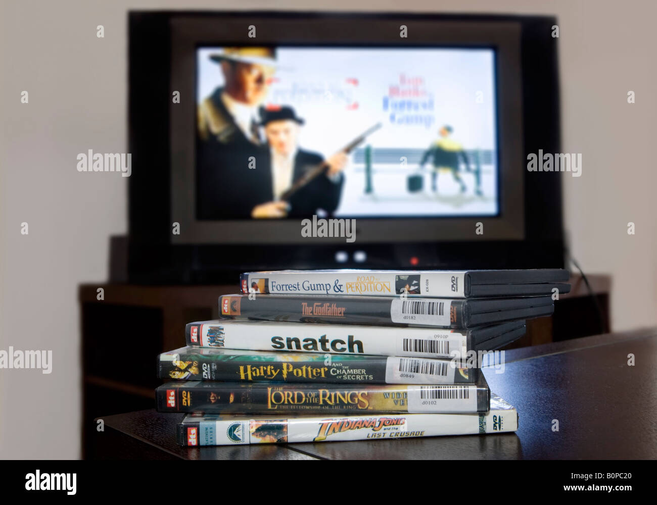 A pile of illegally pirated DVDs of popular movies with a television in