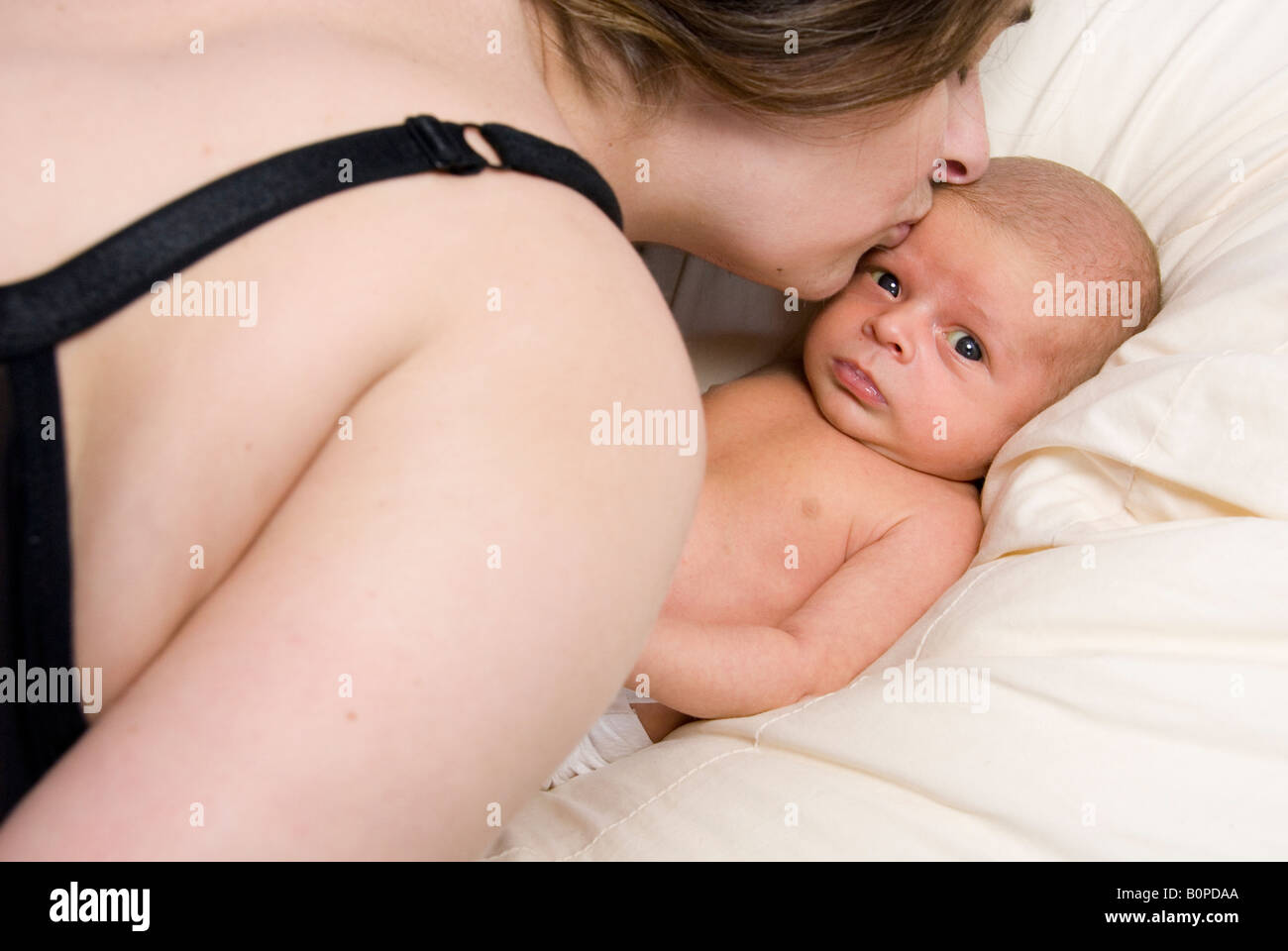 Newborn Baby Boy Joshua Kailas Hudson Aged 20 days Lying in Beanbag Being Kissed by Mother Deborah Waters Stock Photo