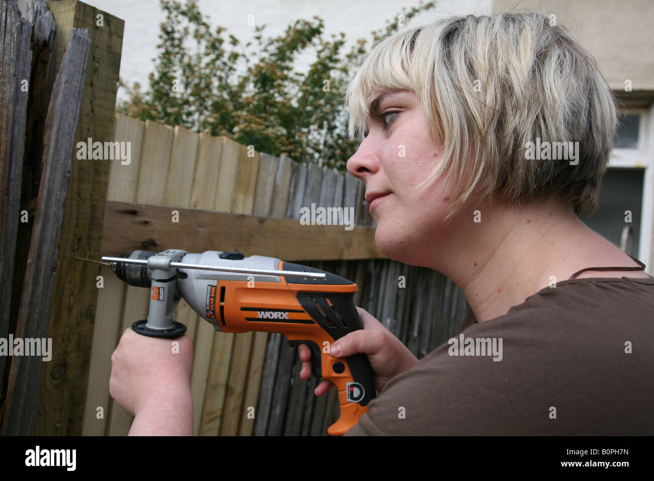 Female putting up or fixing a garden fence using a drill power tool