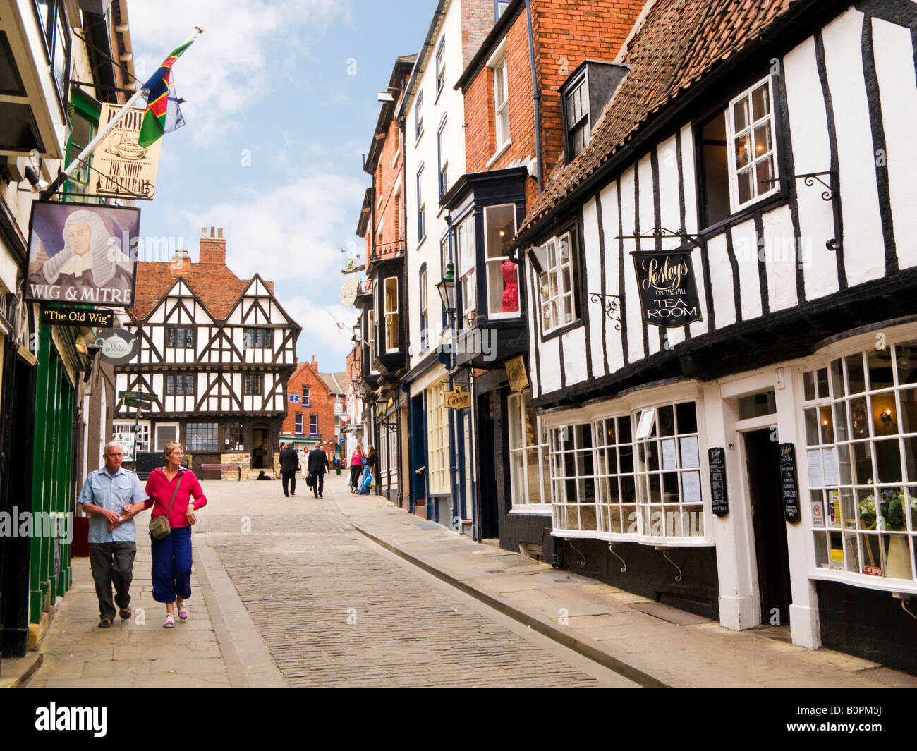 Tourists in Lincoln, UK walking past a traditional pub and tea room on Steep Hill, Lincolnshire, UK Stock Photo