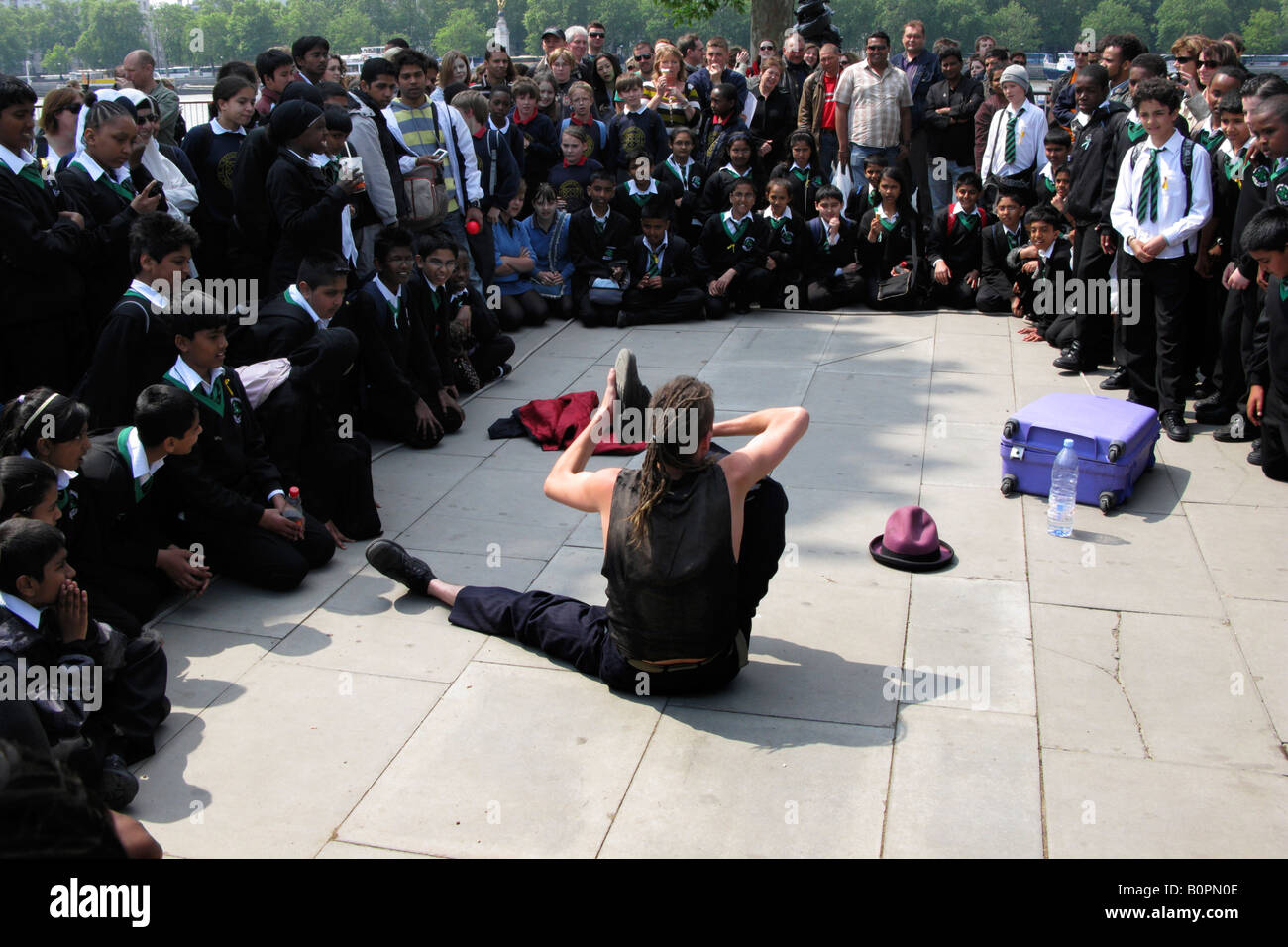 Contortionist admired by a group of school children on London's South Bank Stock Photo