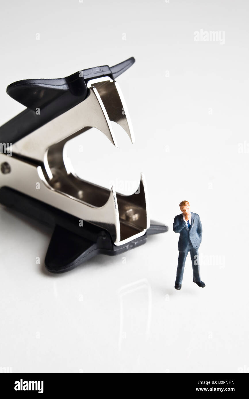 Businessman figurines standing next to a staple remover Stock Photo
