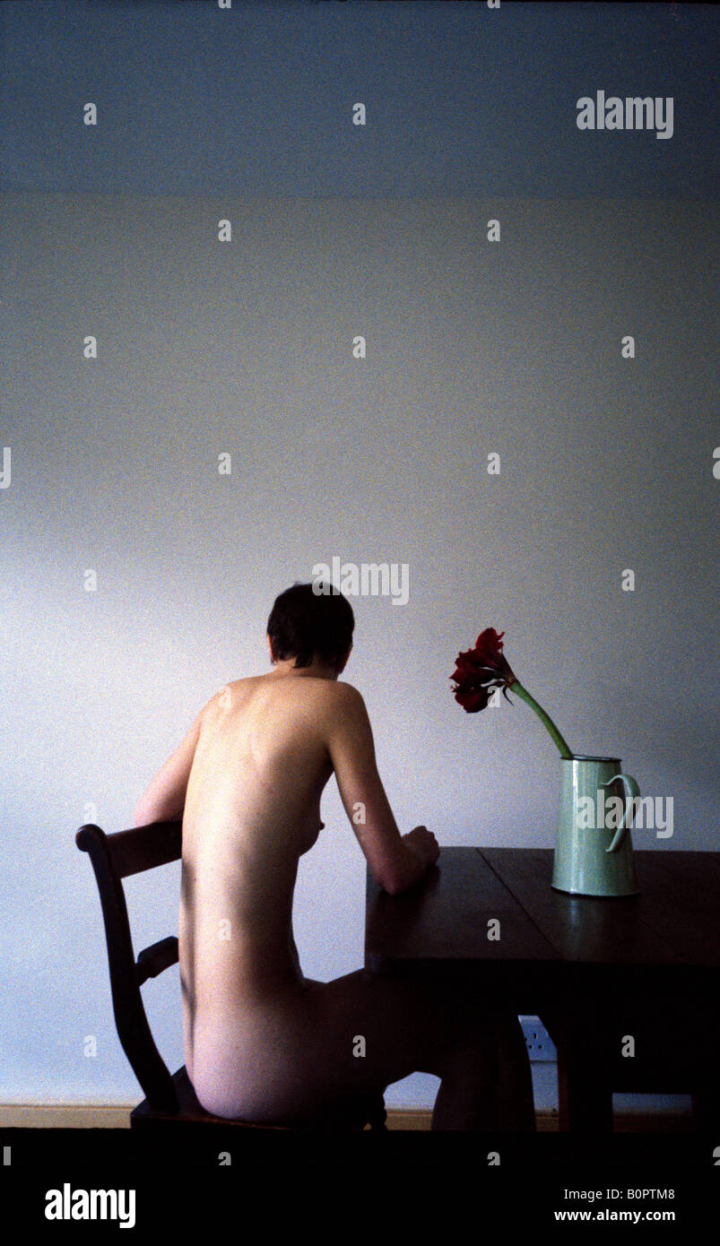girls camera nude photograph a nude girl with her back to camera sits at a table on which stands a vase  with a red flower Stock Photo - Alamy
