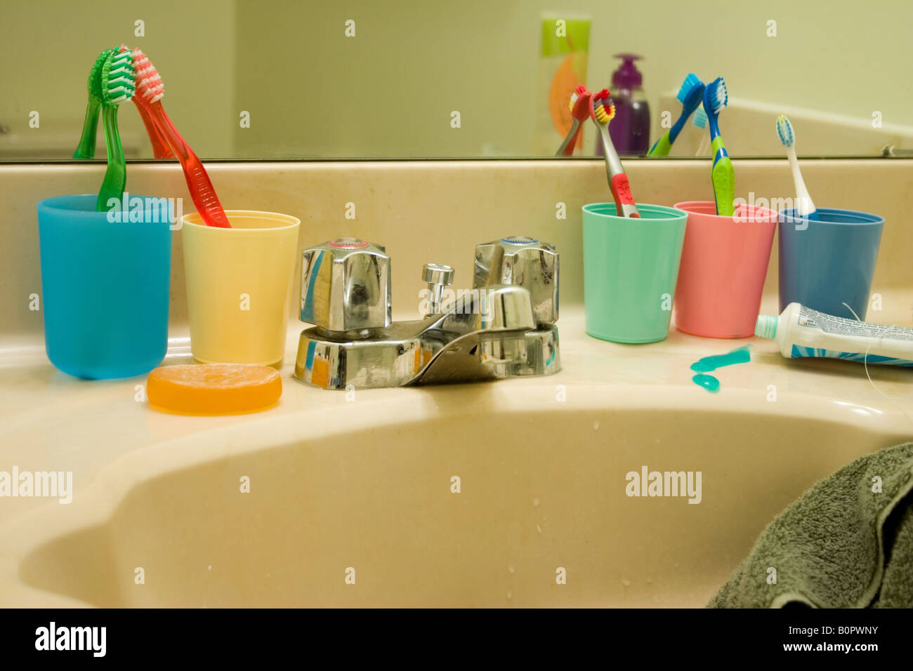 Toothbrushes for each member of the family lined up around bathroom sink. Stock Photo