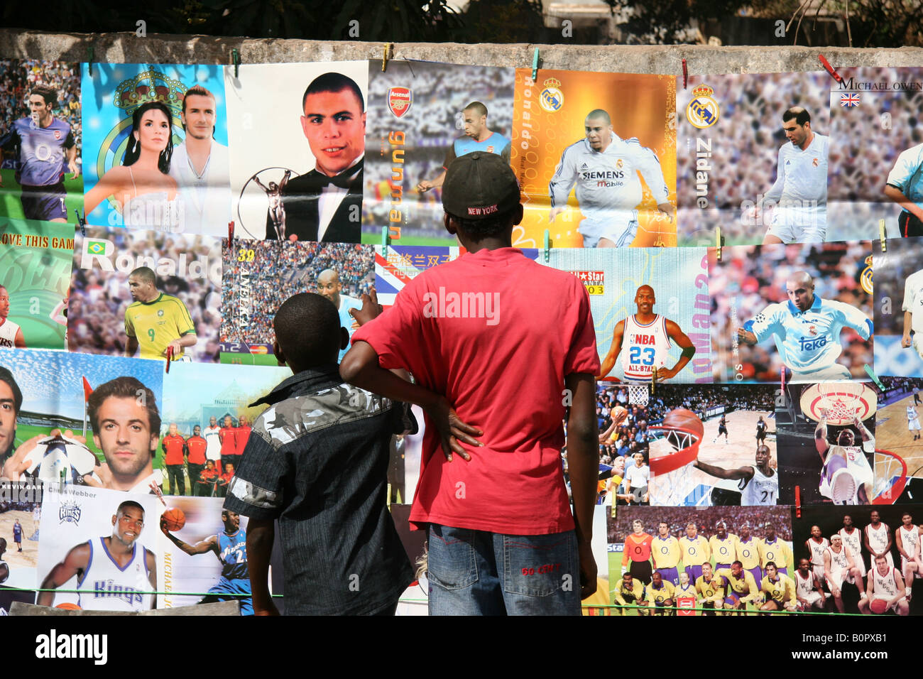 Two boys dreaming away by looking at postes with famous pop and sports stars Stock Photo