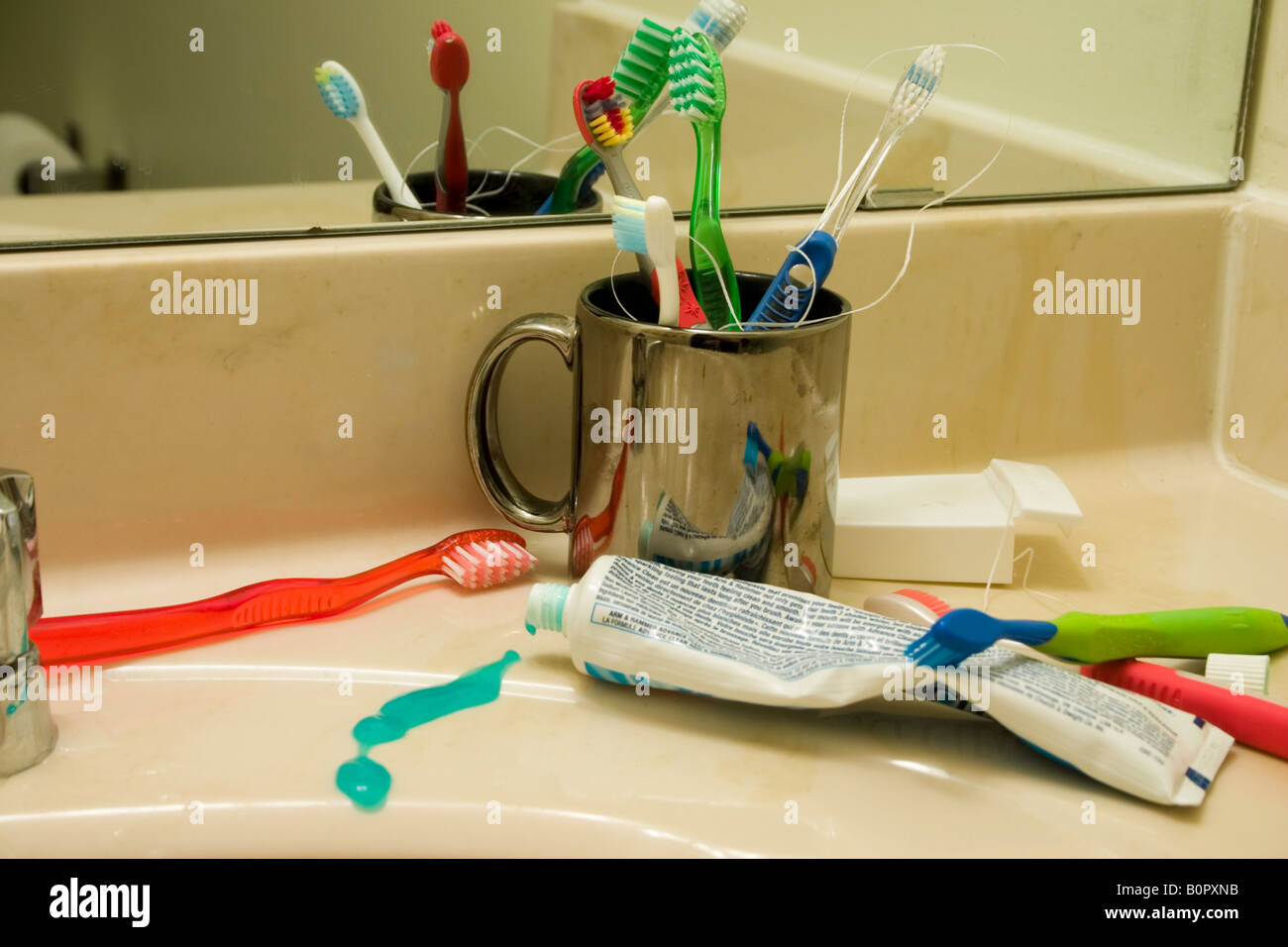 A messy family bathroom with variety of toothbrushes around the sink Stock Photo