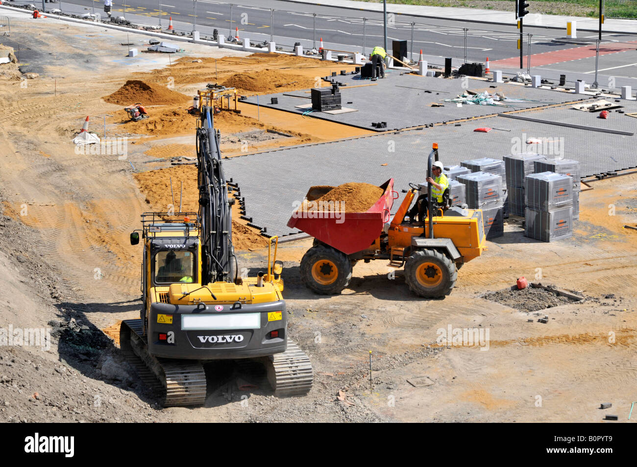 Construction site with dumper truck and excavator machines in use on car park block laying project Stock Photo