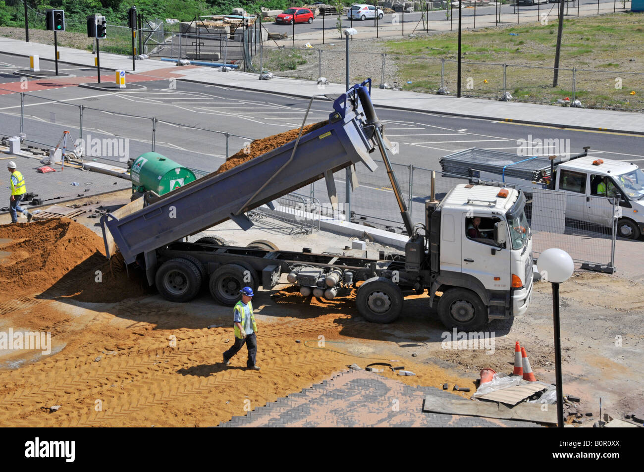 Construction site delivery lorry tips new delivery of sand for use on car park block laying project Stock Photo