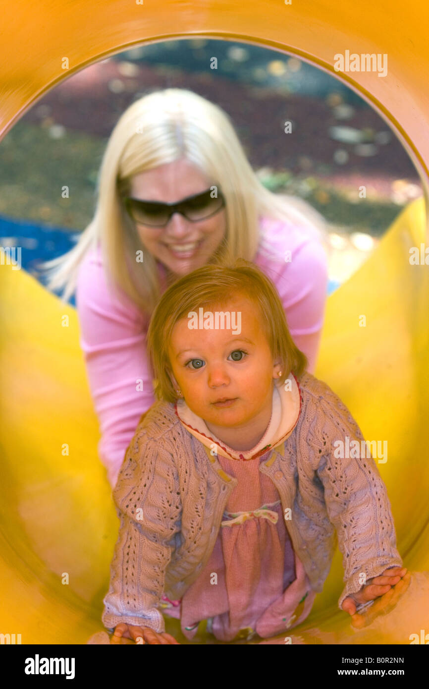 32 year old mother helping her 15 month old daughter down a slide in Tampa Florida Stock Photo