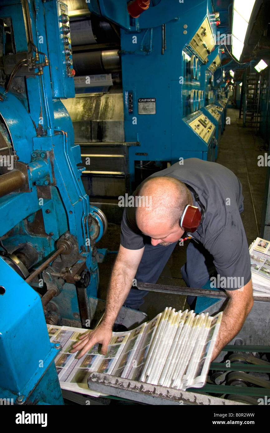 Pressman pulling newspapers from the rotary printing press for the