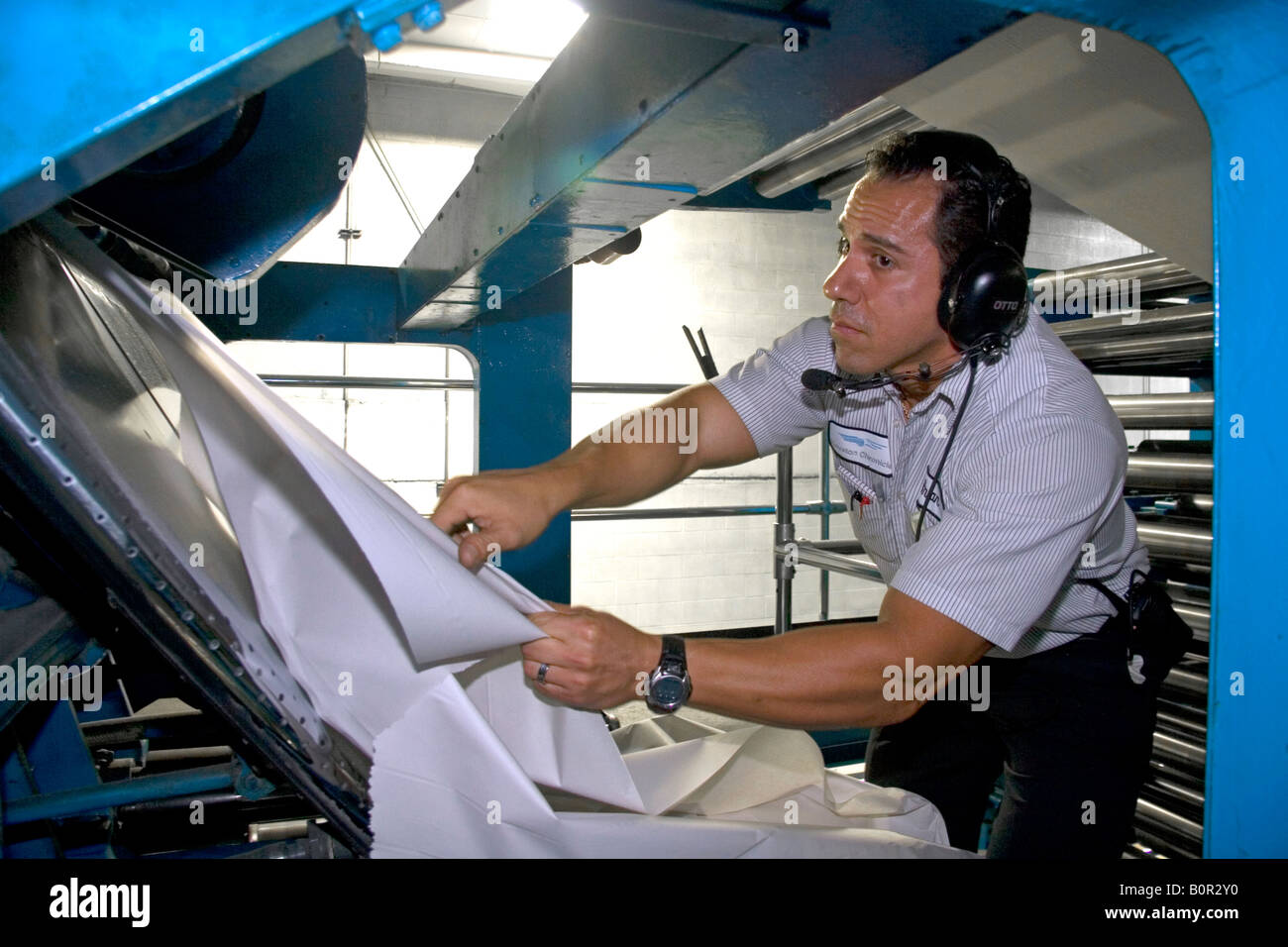 Worker clearing a torn web from the rotary printing press at the Houston Chronicle in Houston Texas Stock Photo