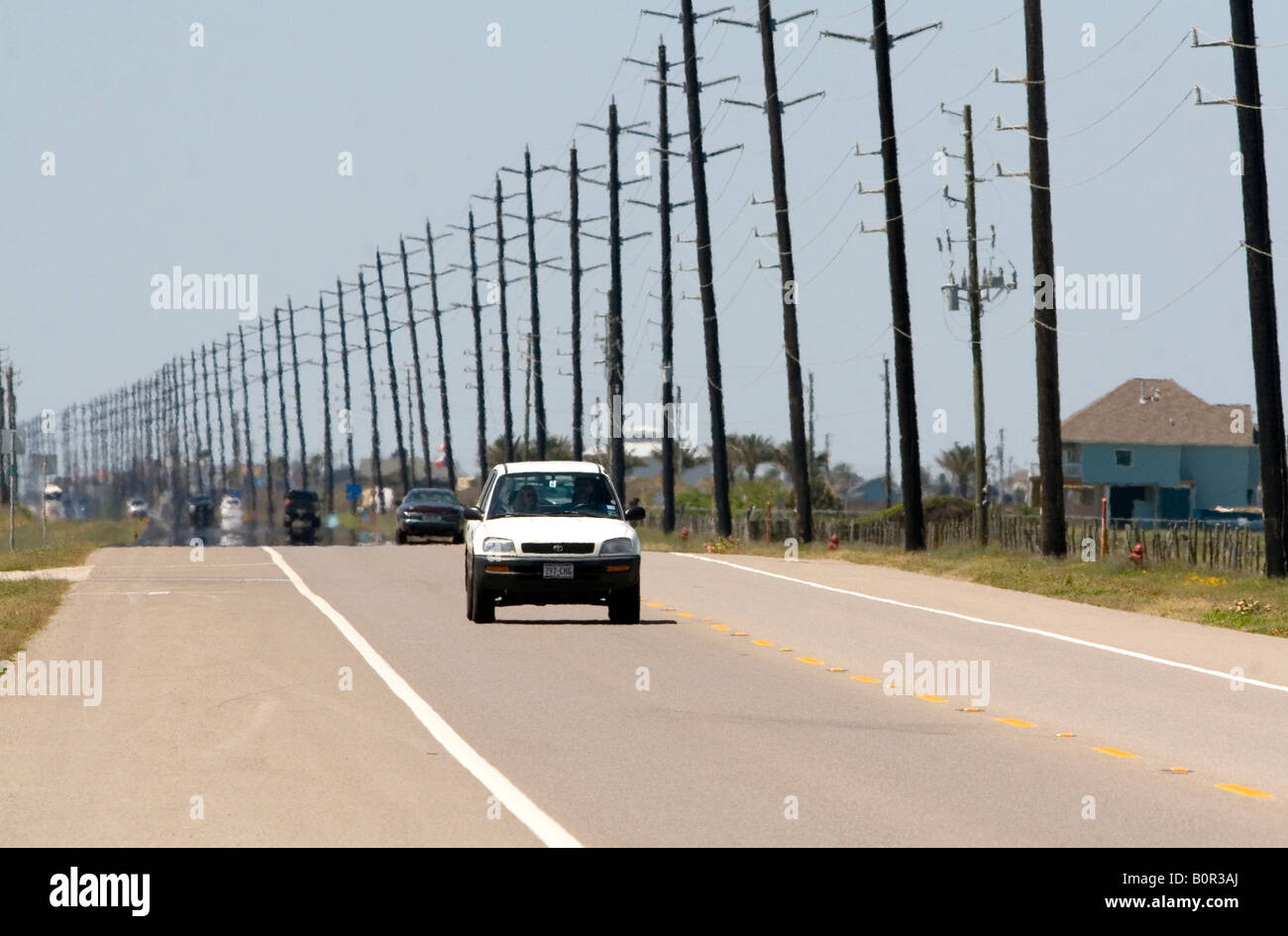 Utility poles line the highway on Galveston Island in Galveston Texas Stock Photo