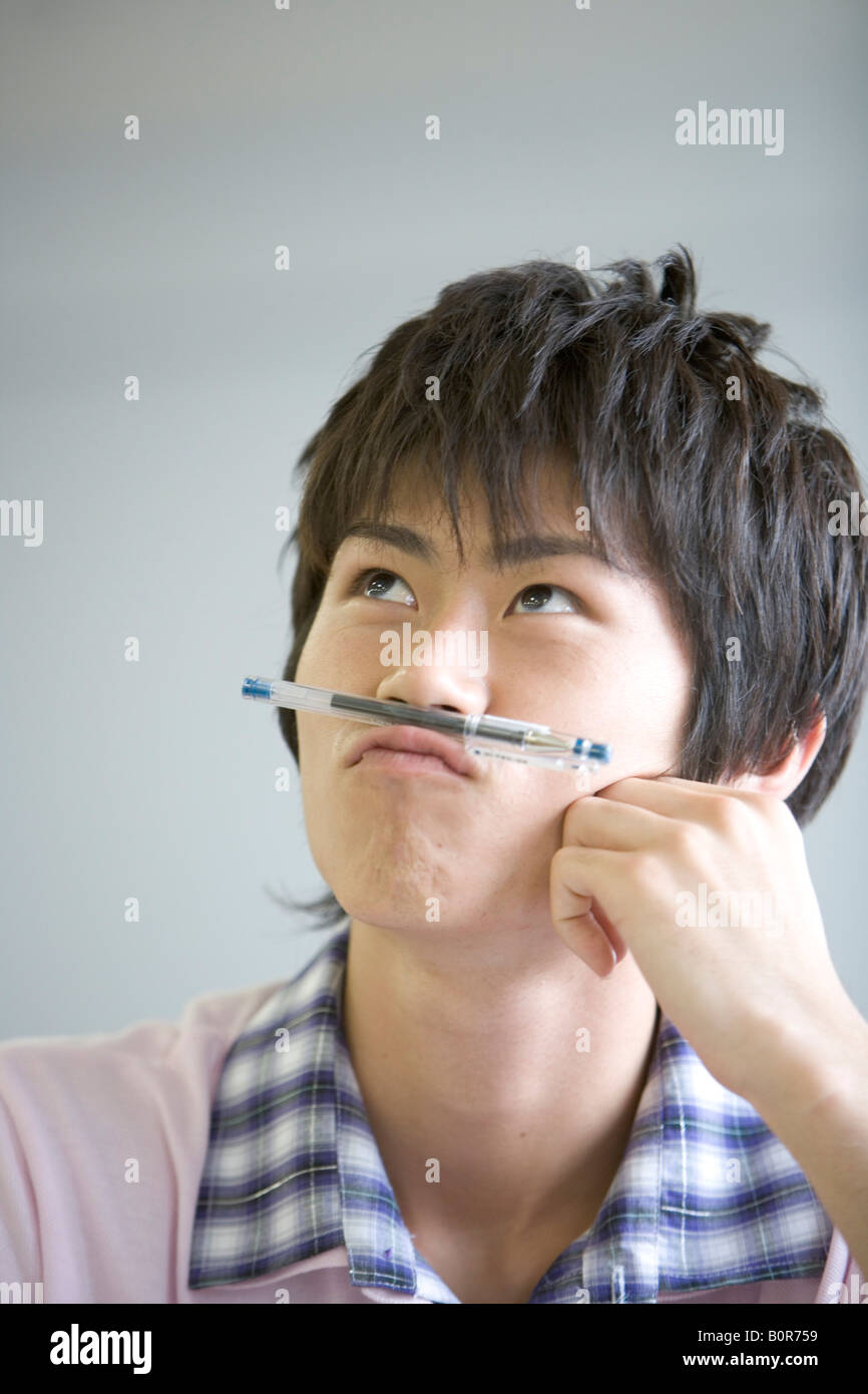 Young man with pen under nose Stock Photo - Alamy