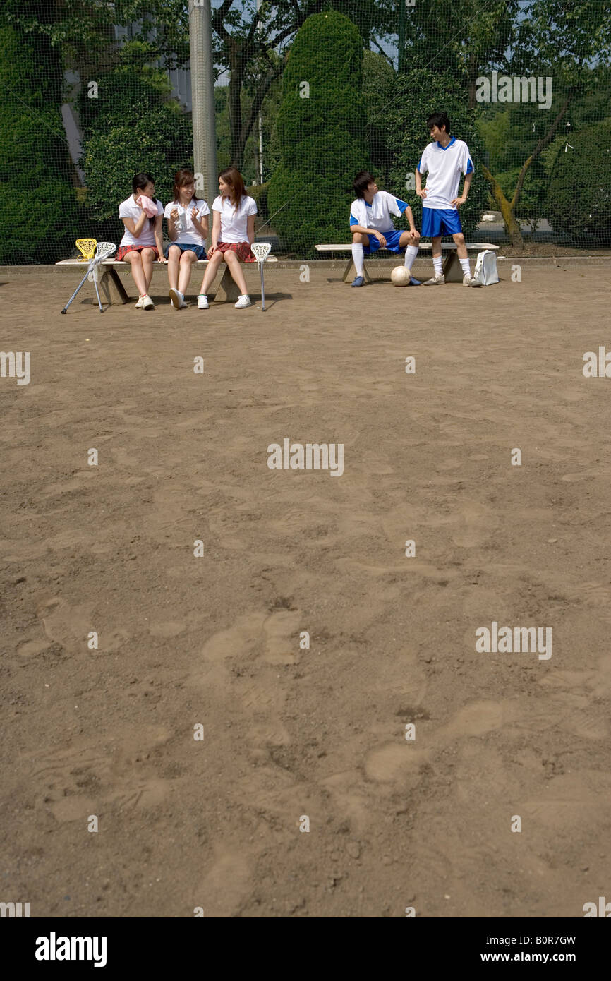 Three girls and two boys sitting on benches during physical education classes Stock Photo
