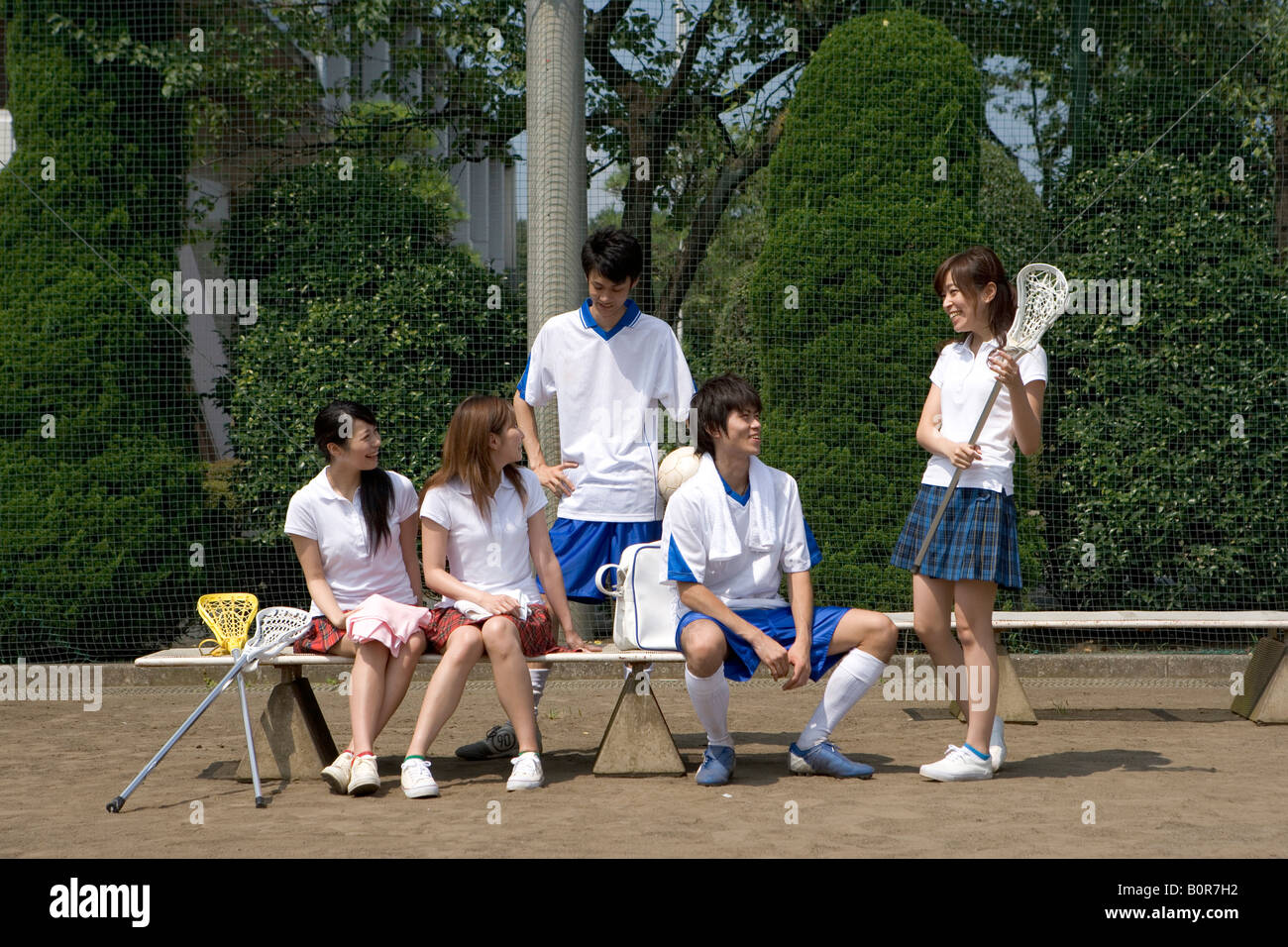 Three girls and two boys sitting on bench during physical education classes Stock Photo