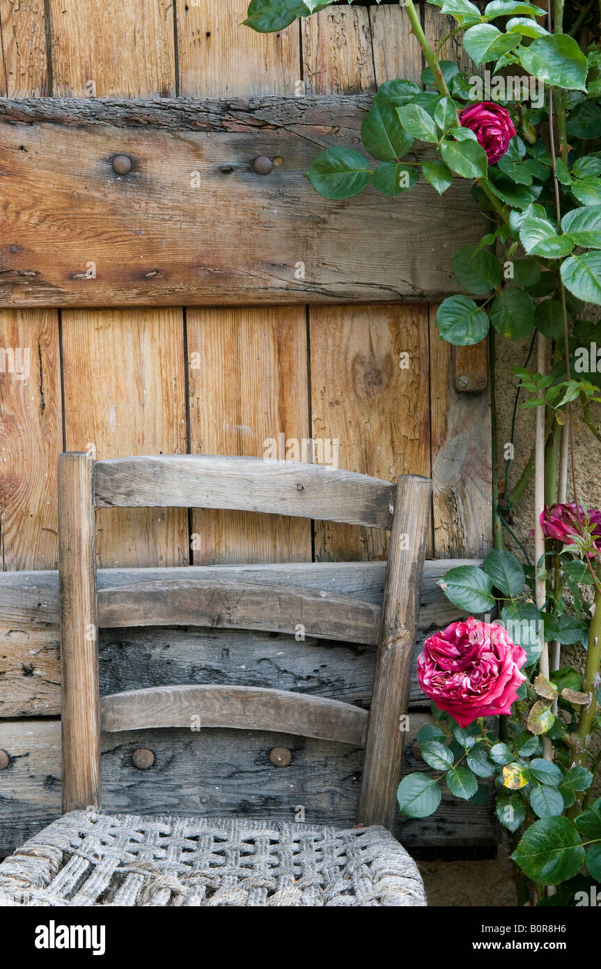 old wooden chair and door with red roses, provence, france Stock Photo