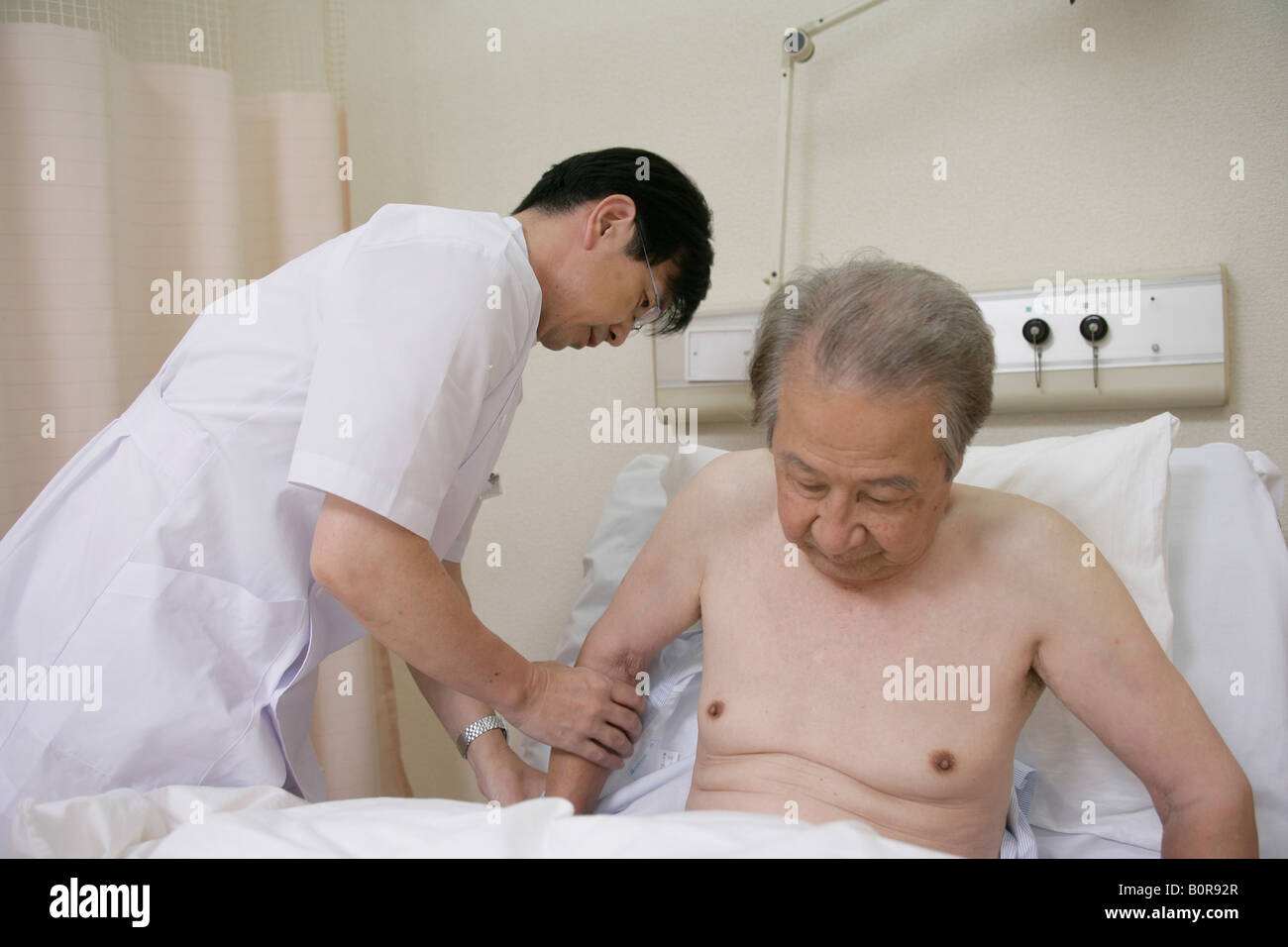 Male nurse undressing patient in hospital bed Stock Photo - Alamy