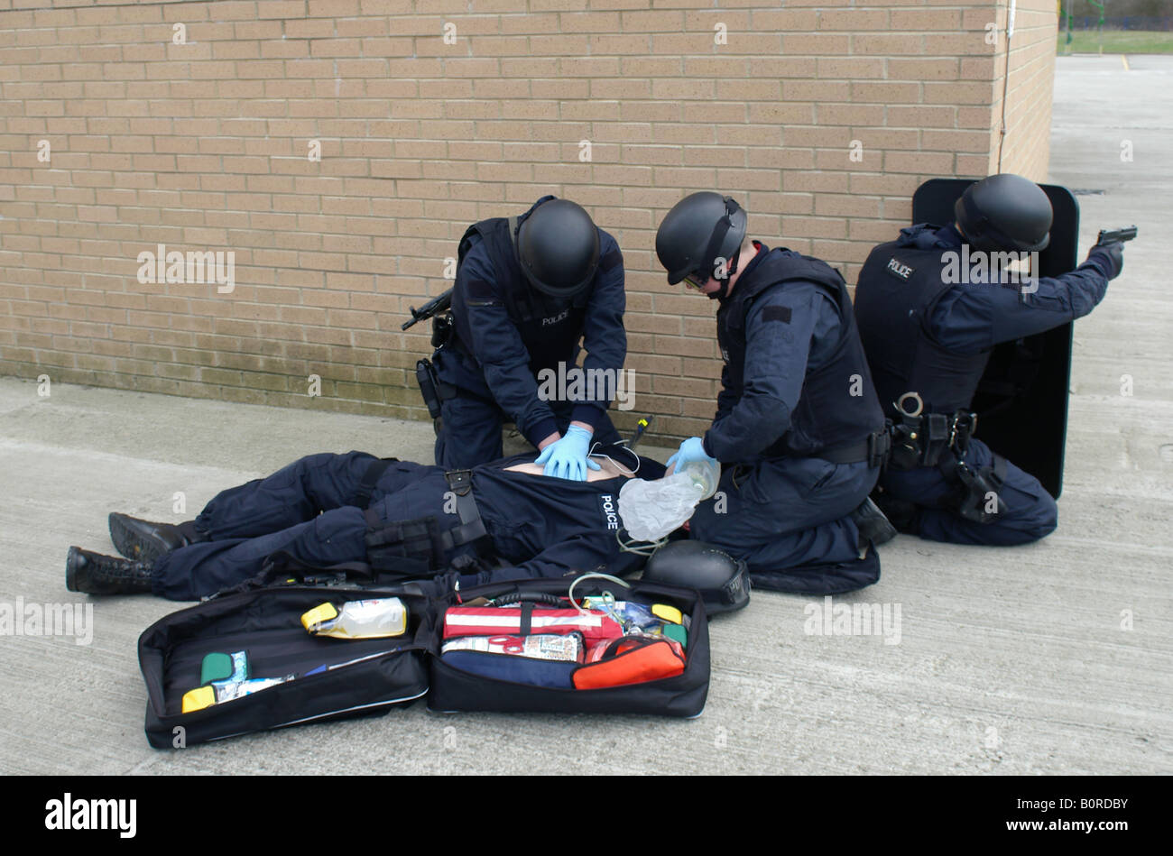 Police firearms officers giving medical assistance to injured officer Stock Photo