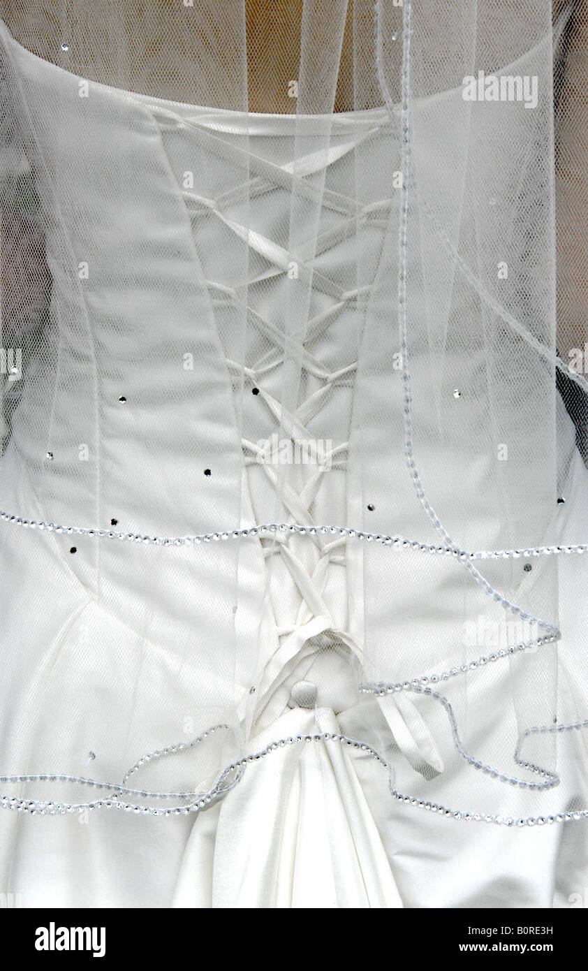 The back of a bride's white wedding dress showing the lacing and her