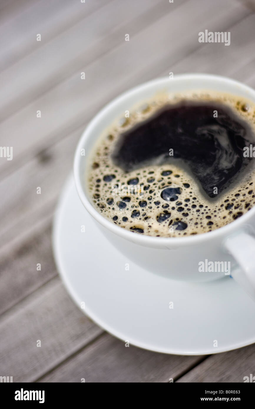 Shallow depth of field image of a cup of coffee in a white cup on a wooden table Stock Photo