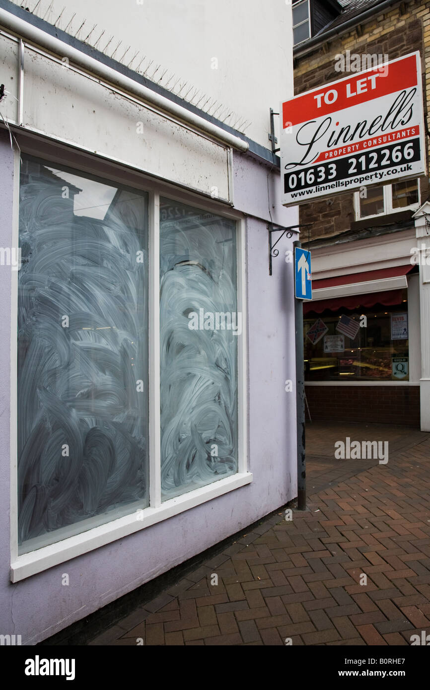 Whitewashed window of closed down shop with To Let agency sign