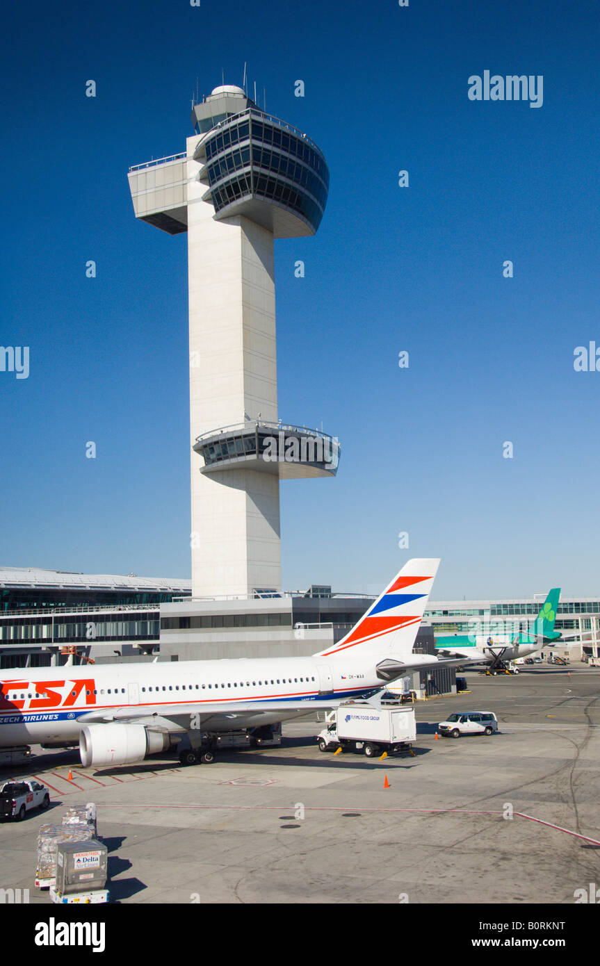 The JFK International airport air traffic control tower with airplanes parked at the terminal Stock Photo
