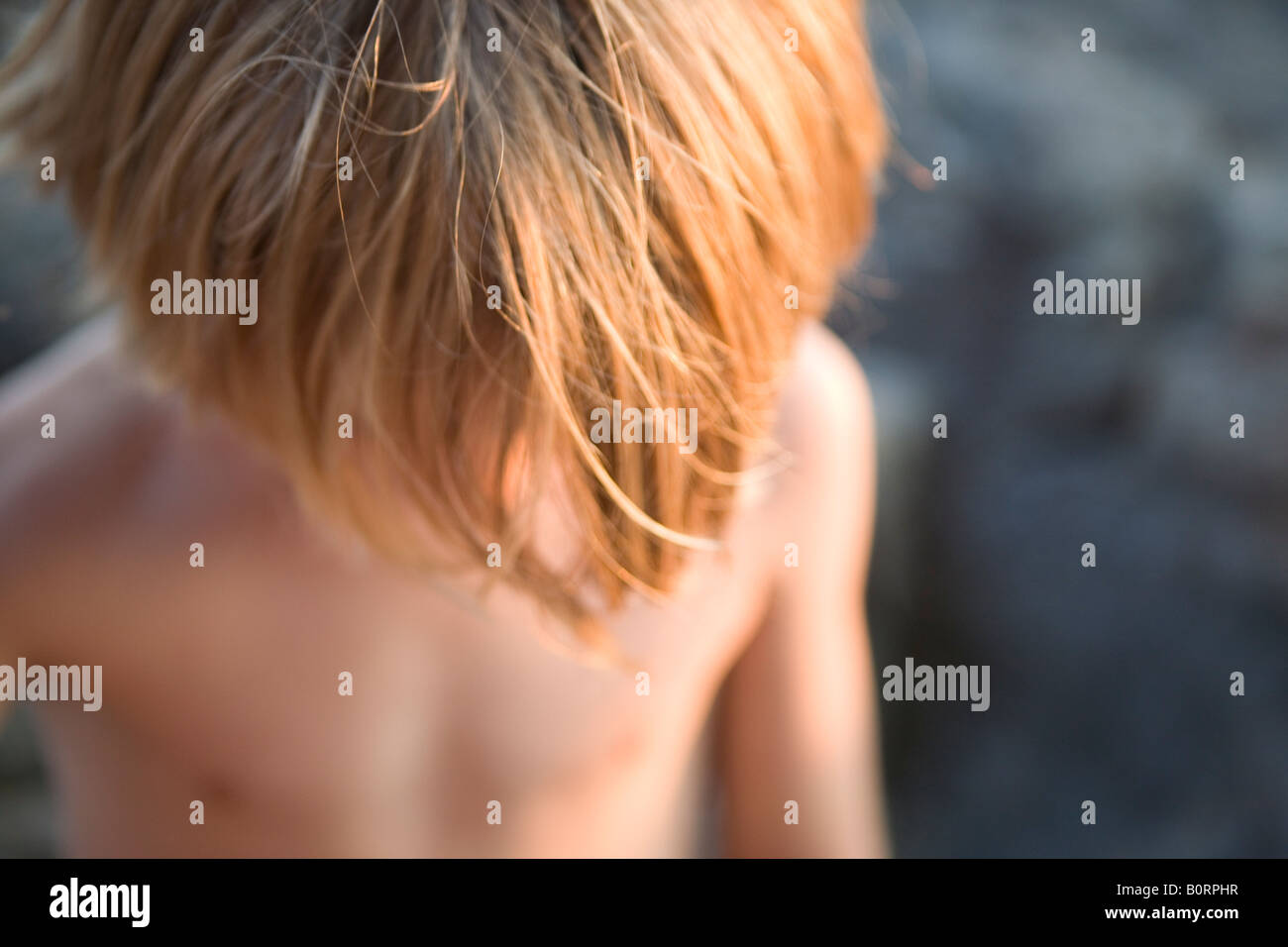 young boy with head down shows hair in warm sunlight 8 years old Stock Photo
