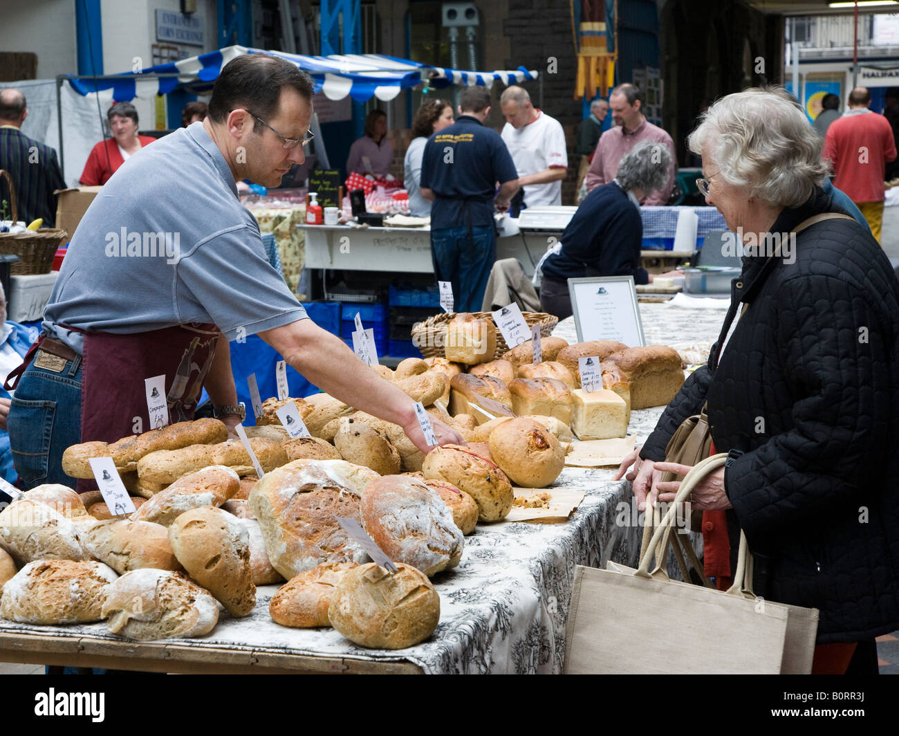 Selling hand made bread at indoor farmers market Abergavenny Wales UK Stock Photo