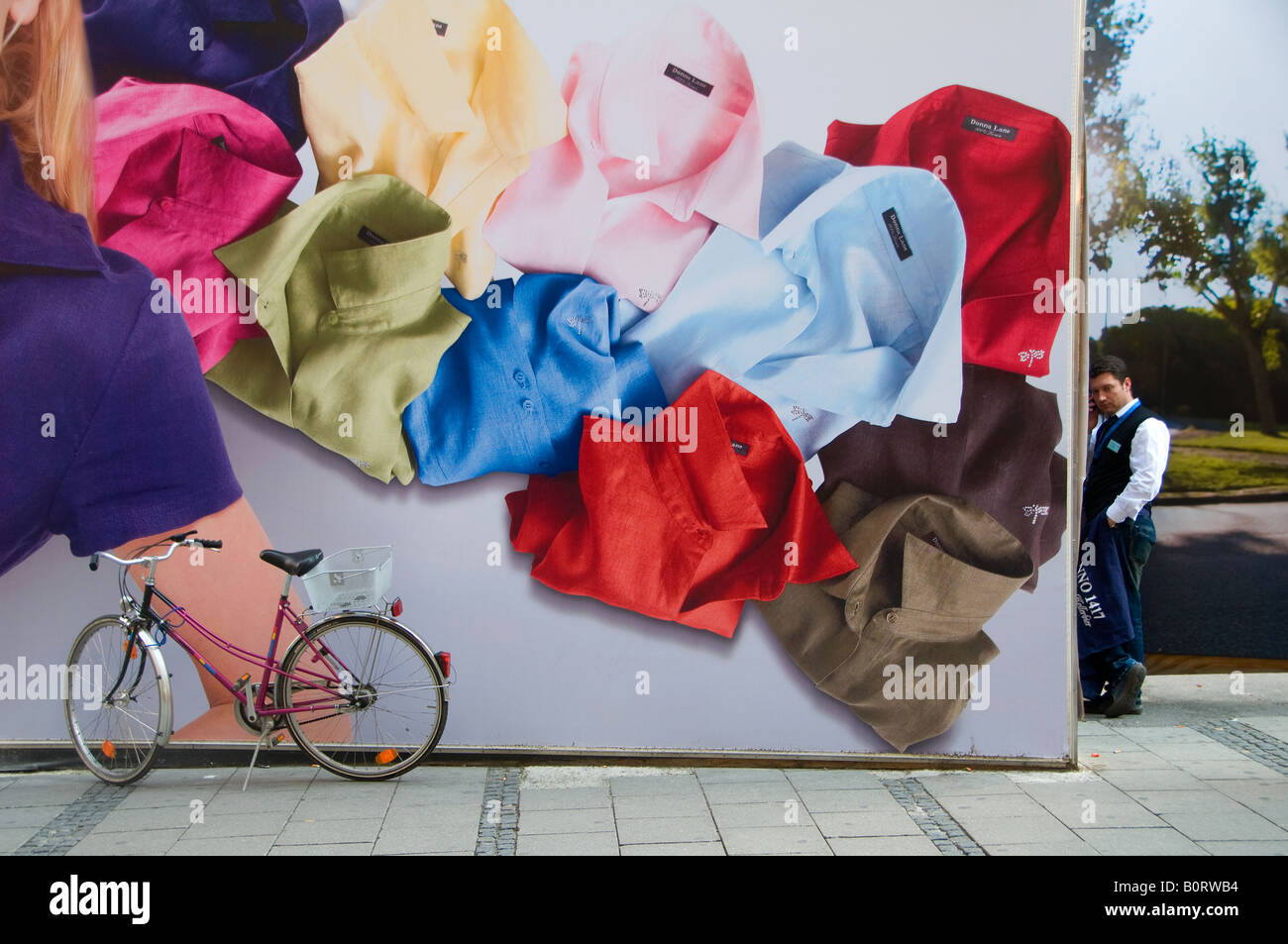A young German stands by a huge poster advertising clothings in Kaufinger street Downtown in the city of Munich capital of Bavaria Germany Stock Photo